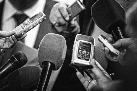 Journalists with recording equipment flocking around important people. Black and white retro style...