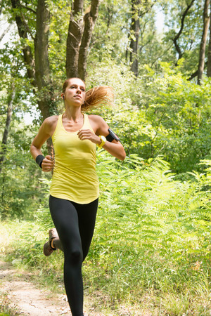 Relaxed young woman jogging and listening musicの写真素材