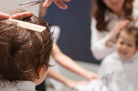 Little boy at hairdresser. Focus on back of the head, blurred mirror reflectionの写真素材