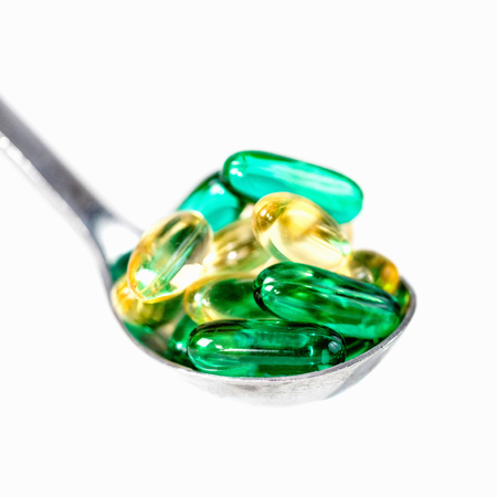 Spoonful of vitamin pills, isolated on whiteの写真素材
