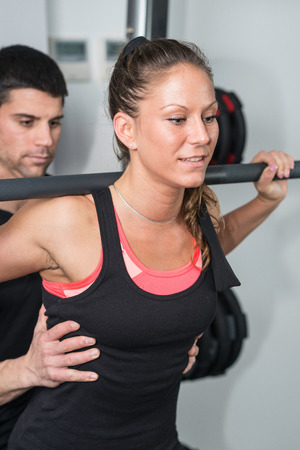 Personal training - Fitness trainer helping his client with weights in gymの写真素材