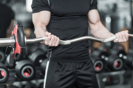 Young man working out with barbell weights in gymの写真素材
