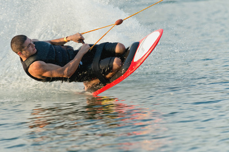 Young man doing a kneeboarding stunt at high speedの写真素材