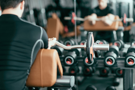 Young man working out with barbell weights in gymの写真素材