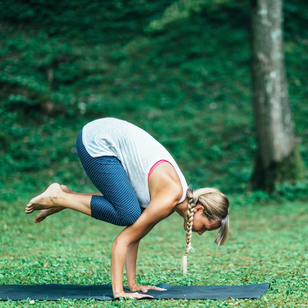 Young woman doing yoga, crow position or Bakasanaの写真素材