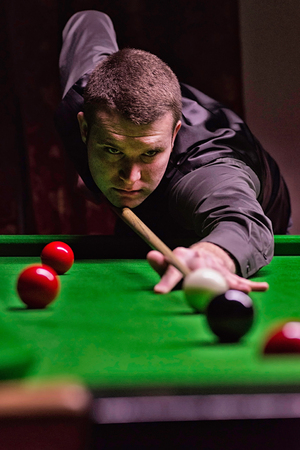 Professional snooker player taking a shot. Image taken in ambient light, slightly toned for athmosphereの写真素材