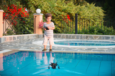 Cute boy playing by the pool with remote control boatの写真素材