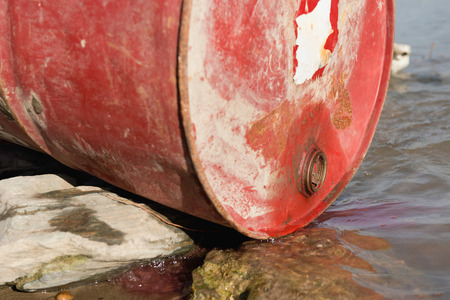 Chemical substance leaking into the water from discarded barrelの写真素材