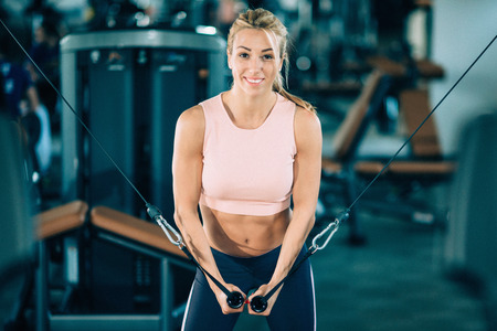 Cable crossover machine workout. Beautiful smiling woman looking at camera.の写真素材