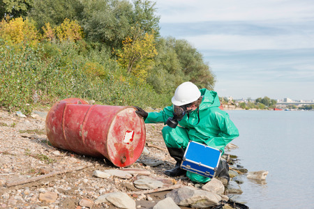 Environment inspector in the field checking discarded steel drumの写真素材