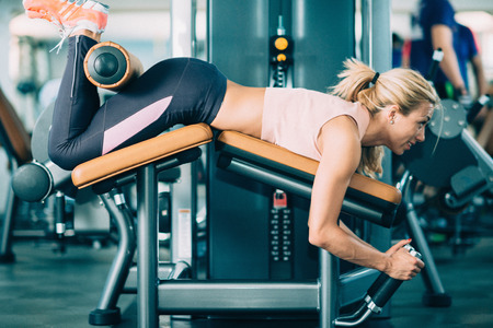 Female athlete exercising on lying leg curls machine in the gymの写真素材