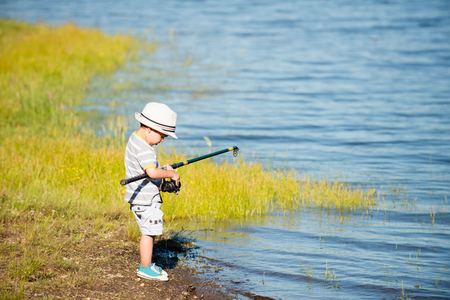 Little boy on the lake, struggling with fishing rodの写真素材