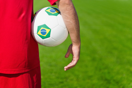 Soccer player holding ball with Brazilian flagsの写真素材