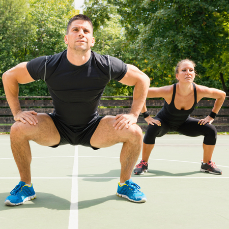 Insanity workout trainer doing squats with female athleteの写真素材