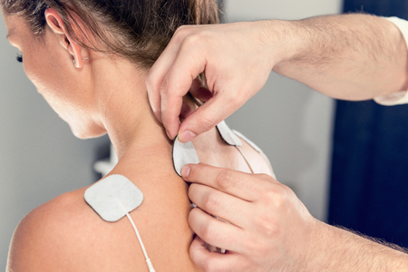 TENS treatment in physical therapy - therapist placing electrodes onto patientの写真素材