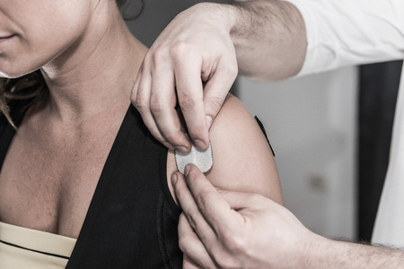 TENS treatment in physical therapy - therapist placing electrodes onto patient's shouldersの写真素材