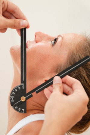 Physical therpist measuring angle of mobility of an athletes neck. Focus on eye.の写真素材