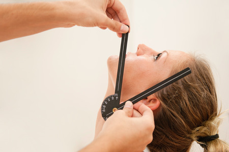 Physical therapis measuring neck mobility angles of a female athleteの写真素材