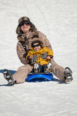 Mother and child sledding on a snowy mountainの写真素材