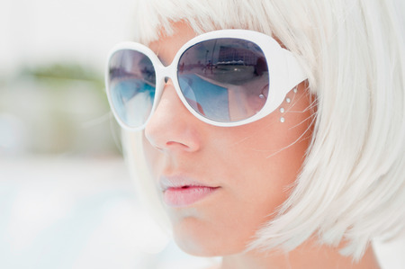 Fancy blonde girl with white sunglasses. High key, shallow depth of fieldの写真素材