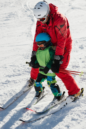 Ski instructor with little boy on skiing classの写真素材