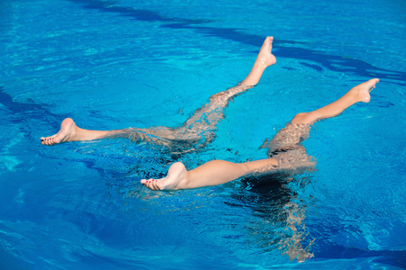 Synchronized swimming duet performing in swimming poolの写真素材