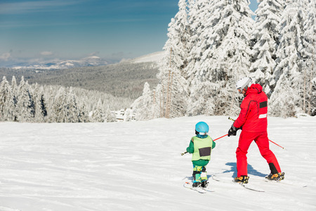 Little boy skiing downhill with ski instructorの写真素材