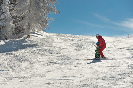 Father holding son, skiing together down the slopeの写真素材