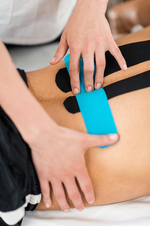Physical therapist placing kinesio tape on patient's backの写真素材