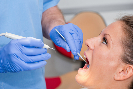 Dentist removing dental calculusの写真素材