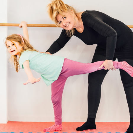 Instructor helping little girl on ballet barreの写真素材