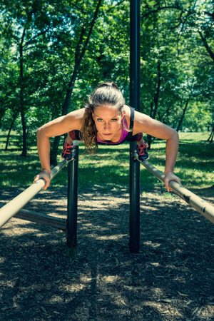 Woman exercising on parallel bars in outdoor gymの写真素材