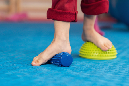 Flat feet physical therapy - Little boy stepping onto spiked rubber rollerの写真素材