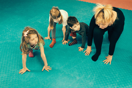 Physical therapist working with group of little children, addresing spinal development issues, doing simple posture improvement exercises. Toned imageの写真素材