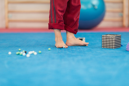 Flat feet physical therapy - Little boy picking up marbles with his feet, developing feet motor skills and flexibilityの写真素材