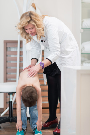 Physical therapist doing medical exam, checking functional status of spine of a little boyの写真素材