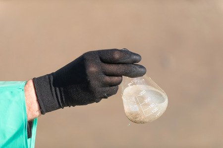 Technician holding sample of dirty waterの写真素材