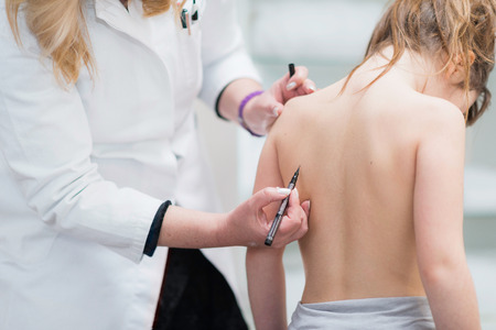 Physical therapist examining posture of a little girl, making marks at her scapula bonesの写真素材
