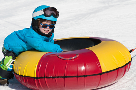Happy little boy with snow tube enjoying the snowの写真素材