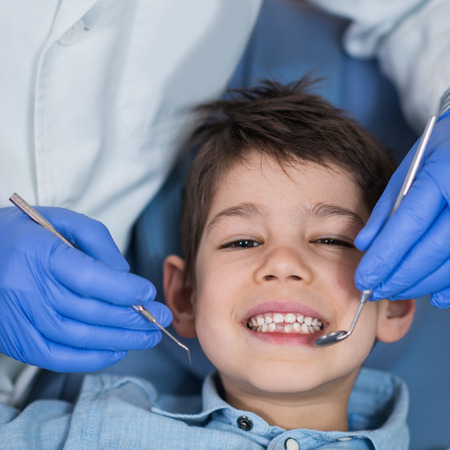 Dentist doing regular dental check-up to little boy.の写真素材