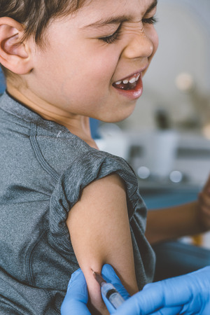 Little boy receives a vaccination in the doctors office.の写真素材