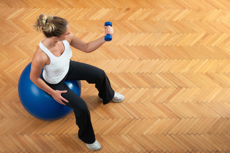 Young female exercise biceps on exercise ballの写真素材