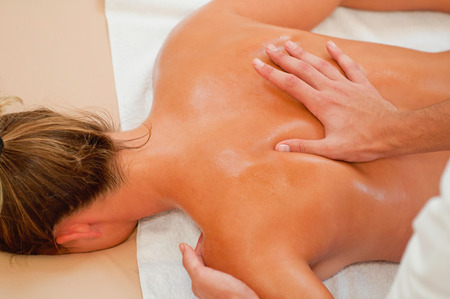 Therapist massaging back of a young womanの写真素材