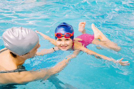 Swimming class - little girl learning to swim with swimming instructorの写真素材
