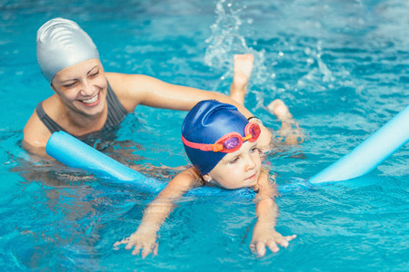 Swimming class - little girl learning to swim with swimming instructorの写真素材