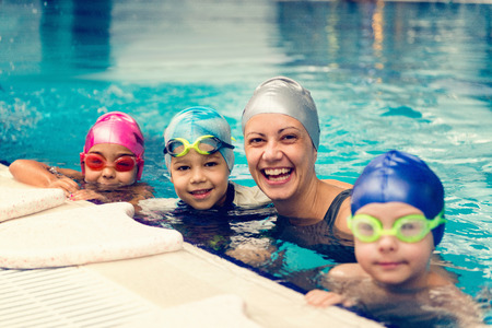 Swimming instructor having fun with group of childrenの写真素材