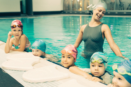 Swimming school for children - Group of children with swimming instructor. Toned imageの写真素材