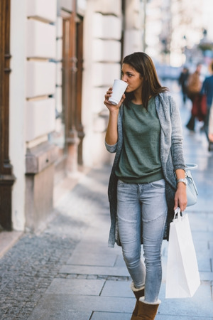 Girl with a take-away coffe in the city looking storesand shoppingの写真素材