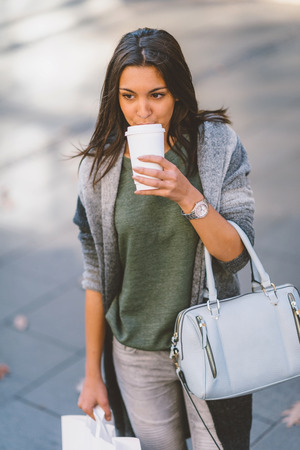 Girl with a take-away coffe in the city looking storesand shoppingの写真素材