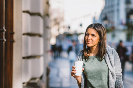 Girl with a take-away coffe in the city looking storesand shoppingの写真素材